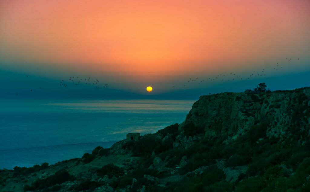 A serene sunset over a calm ocean horizon and rocky cliffs, symbolizing the clarity and peace of a purposeful life.