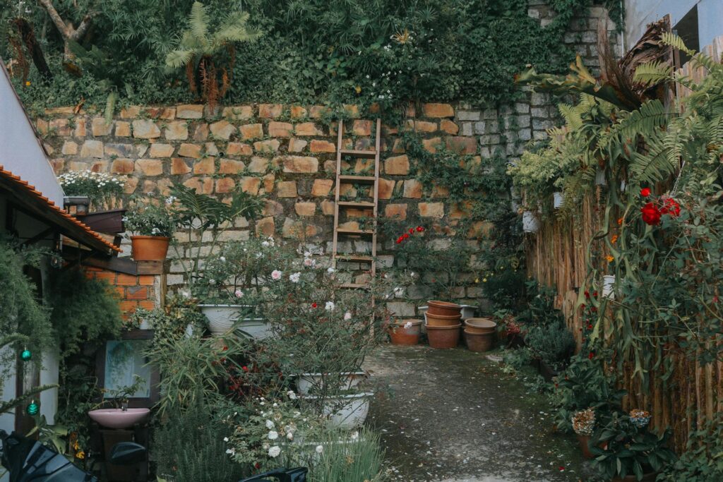 A soulful aesthetic garden courtyard with stone walls, layered greenery, and blooming flowers.